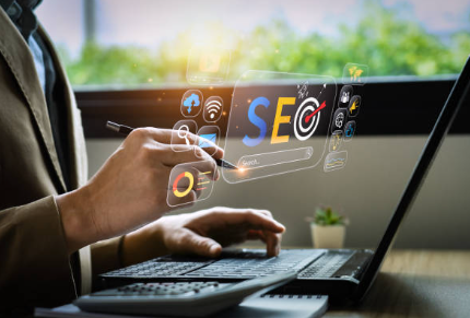 a display of a computer keyboard a hand pointing with a pen to a blurb of virtual screen saying SEO